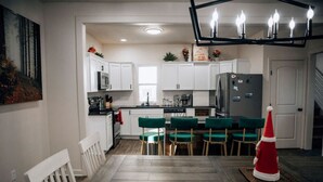 A modern kitchen with white cabinets, a central island with bar stools, and a red Christmas tree. - Amazing 6 bdrm Downtown KC/Near Plaza/UMKC (Kansas City)