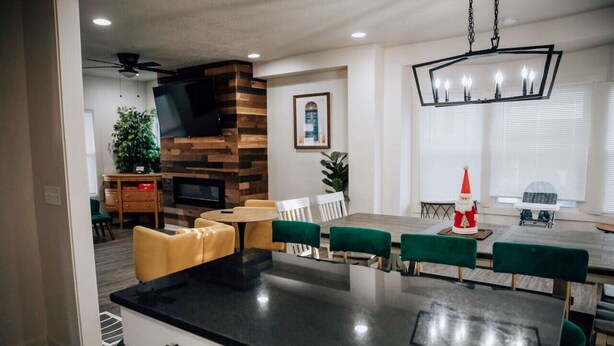 A modern kitchen with a black countertop, green upholstered chairs, and a fireplace. - Amazing 6 bdrm Downtown KC/Near Plaza/UMKC (Kansas City)
