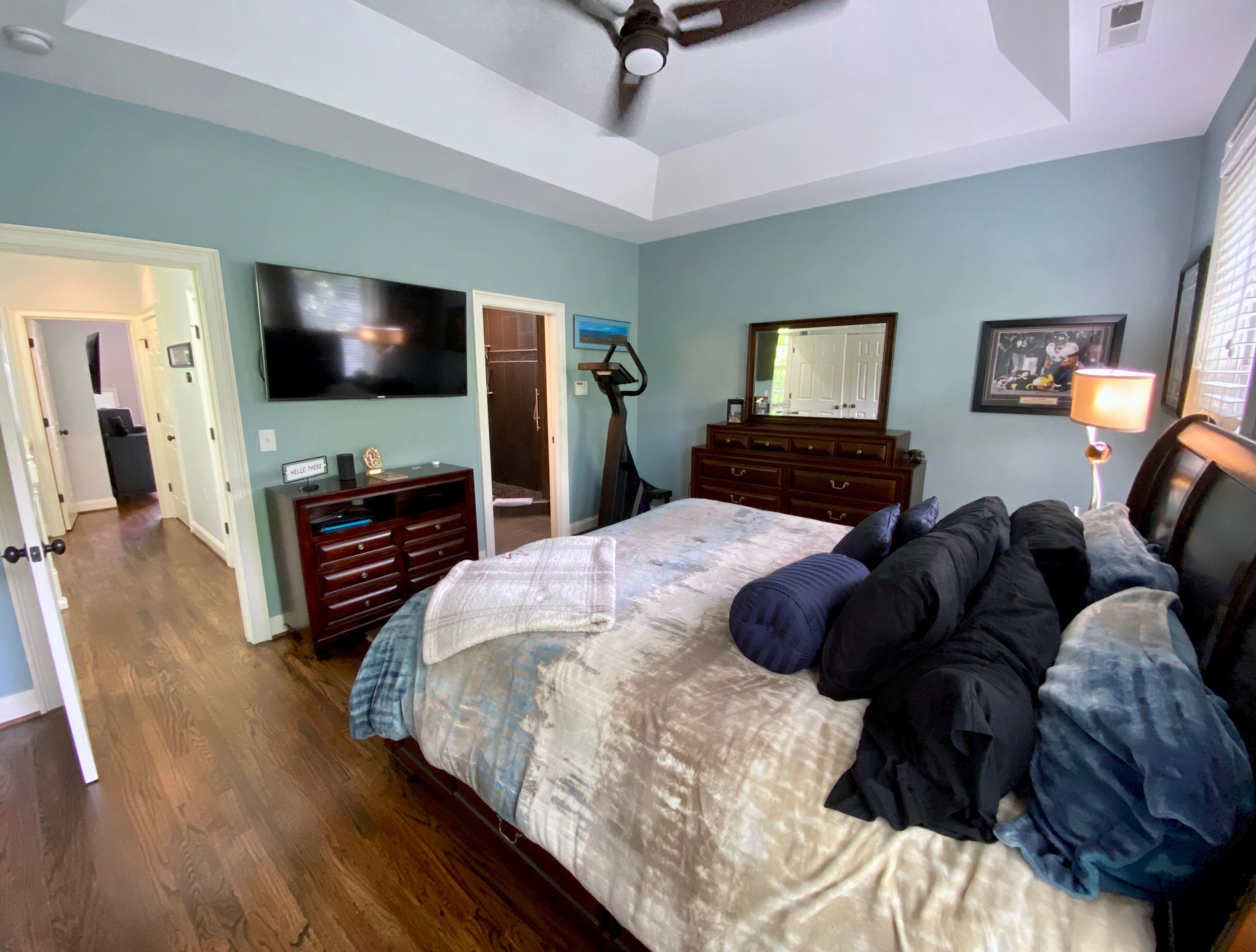 A bedroom with a bed, a dresser, a TV, and a mirror.