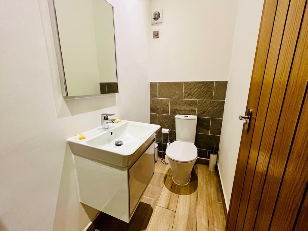 A bathroom with a white sink, a toilet, and a mirror.