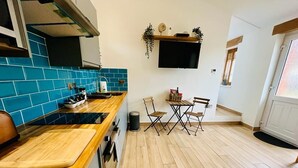 Une cuisine compacte avec des carreaux bleus, un plan de travail en bois et un coin repas comprenant deux chaises et une table.