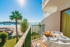 A balcony with a table set for breakfast overlooking a beach and the sea.