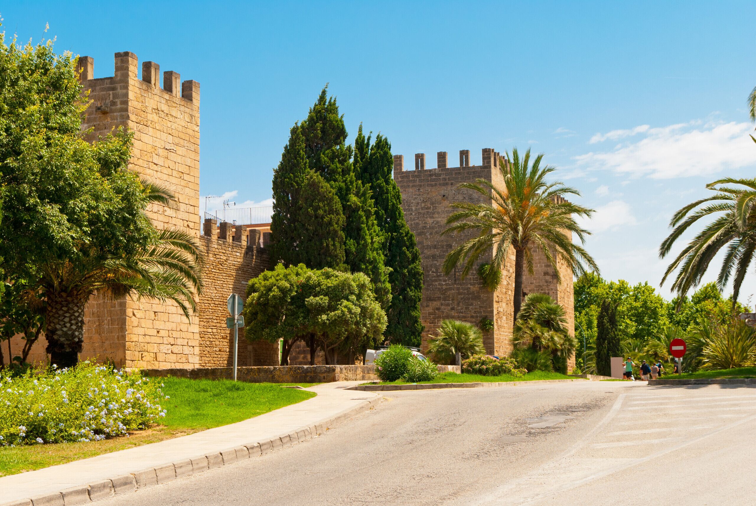 A historic stone building with a prominent tower and a paved road in front.