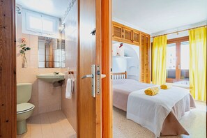 A hotel room with a bathroom, a bed with towels, and a window with curtains.