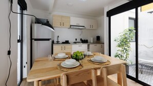 Una cucina moderna con mobili bianchi, una cappa aspirante nera e un'area pranzo con un tavolo in legno apparecchiato per quattro persone.