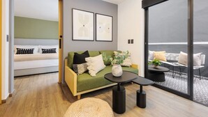Un soggiorno moderno con un divano verde, un tavolino rotondo e un balcone con posti a sedere esterni.