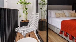 Un balcon avec une chaise blanche, une petite table et des plantes en pot.
