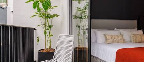 Un balcon avec une chaise blanche, une petite table et des plantes en pot.