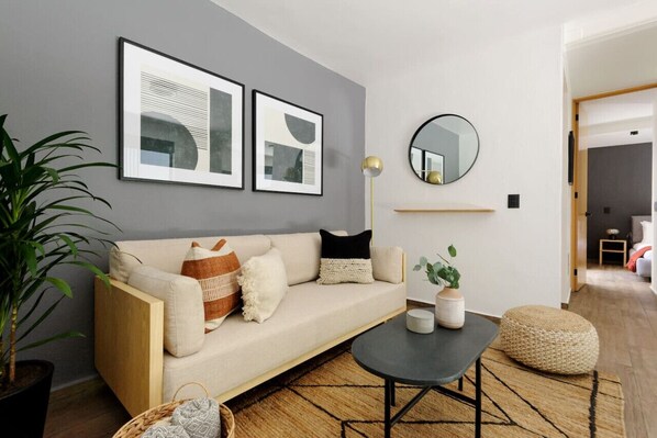 Un salon moderne avec un canapé, une table basse et un grand miroir rond accroché au mur.