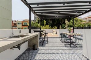 Une terrasse sur le toit, dotée d’un sol carrelé, de sièges extérieurs, d’un évier et d’une pergola.