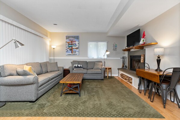 A living room with a sofa, a coffee table, a fireplace, and a television.