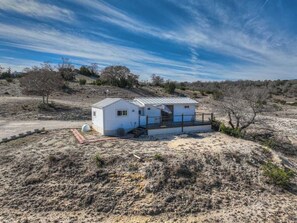 A single-story house with a metal roof, a porch, and a fenced yard. - K Loma Vista with Hill Country Views (Center Point)