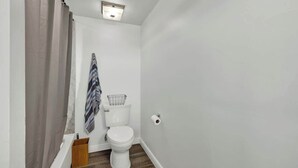 Un baño pequeño y estrecho con inodoro, perchero y cortina de ducha.