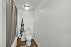 Uma casa de banho pequena com sanita, suporte para toalhas e cortina de chuveiro.
