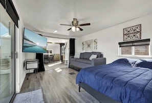 Quarto moderno com uma cama grande, um ventilador de teto, uma televisão de tela plana e vista para o exterior.