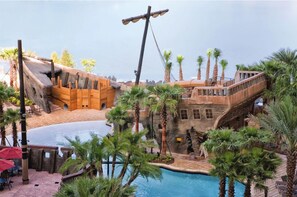 A pool area with a wooden ship structure, palm trees, and a stone building. - 3Bed/2Bath Condo in Gorgeous Orlando Resort Near Disney!! (Lake Buena Vista)
