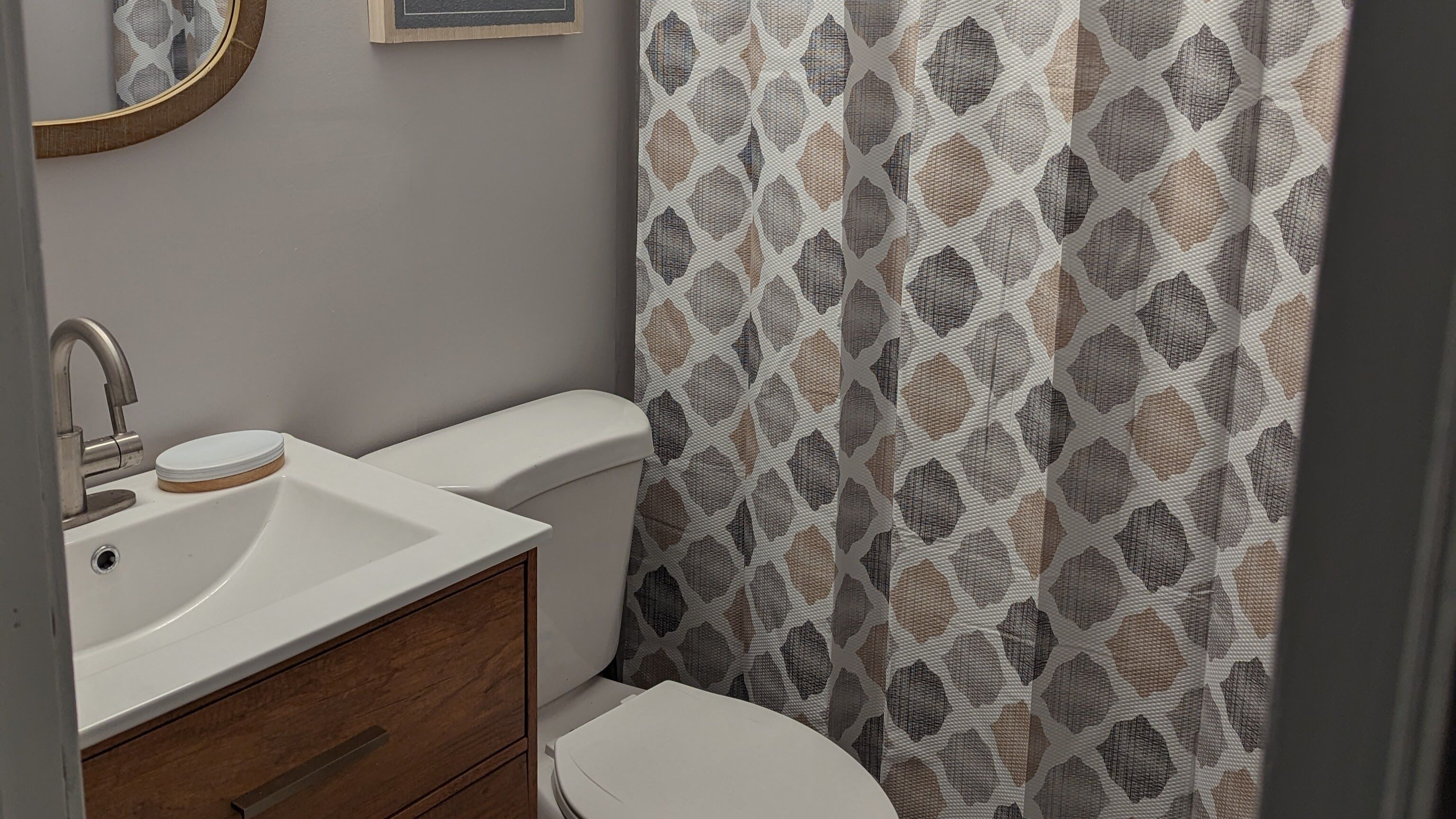 Un baño con lavamanos blanco, armario de madera y retrete.