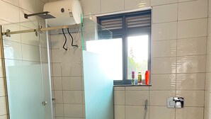 Un baño moderno con cabina de ducha de vidrio, inodoro y ventana que proporciona luz natural.