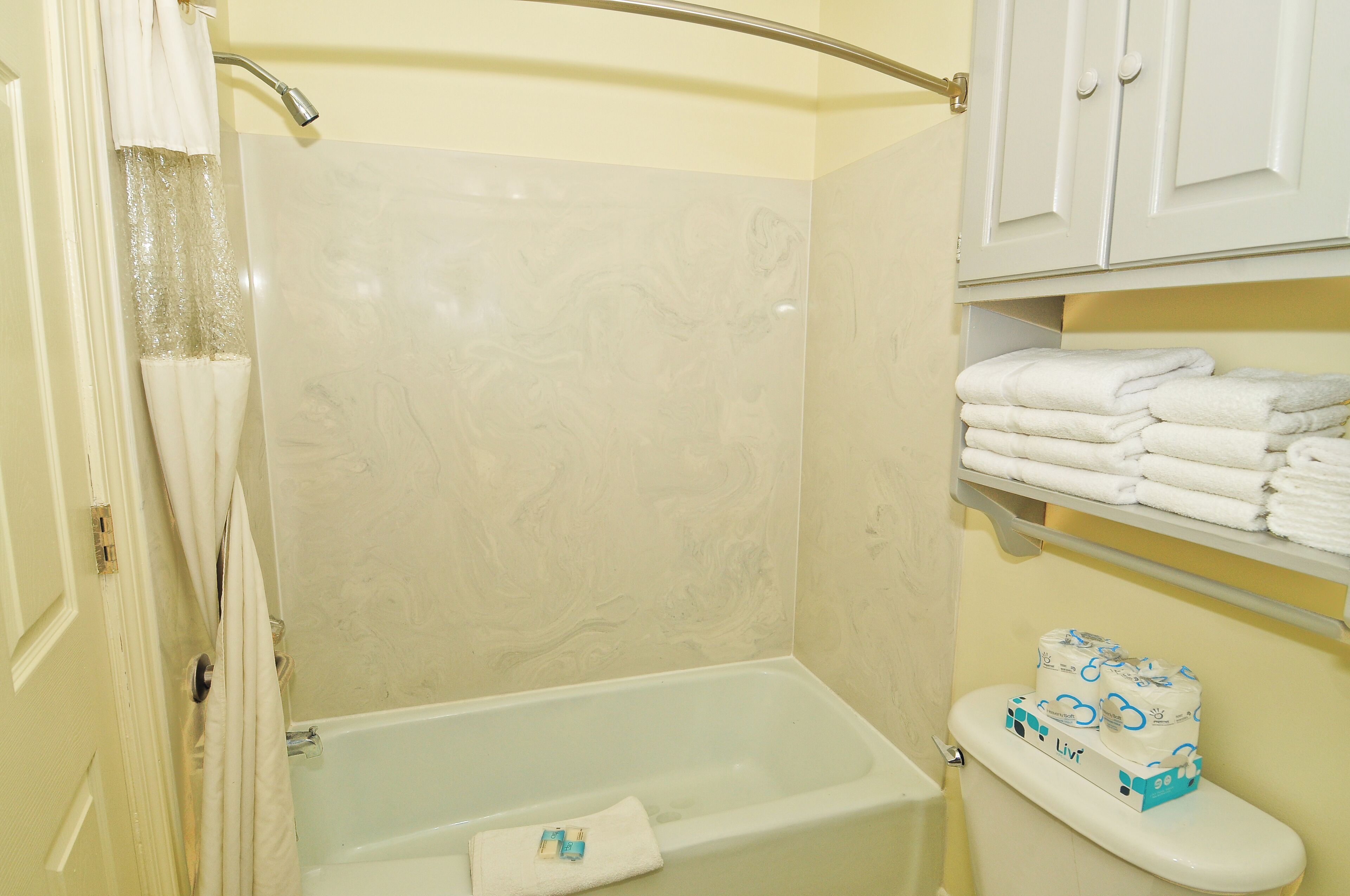 Une salle de bain avec une baignoire, des toilettes et une étagère où sont pliées des serviettes.