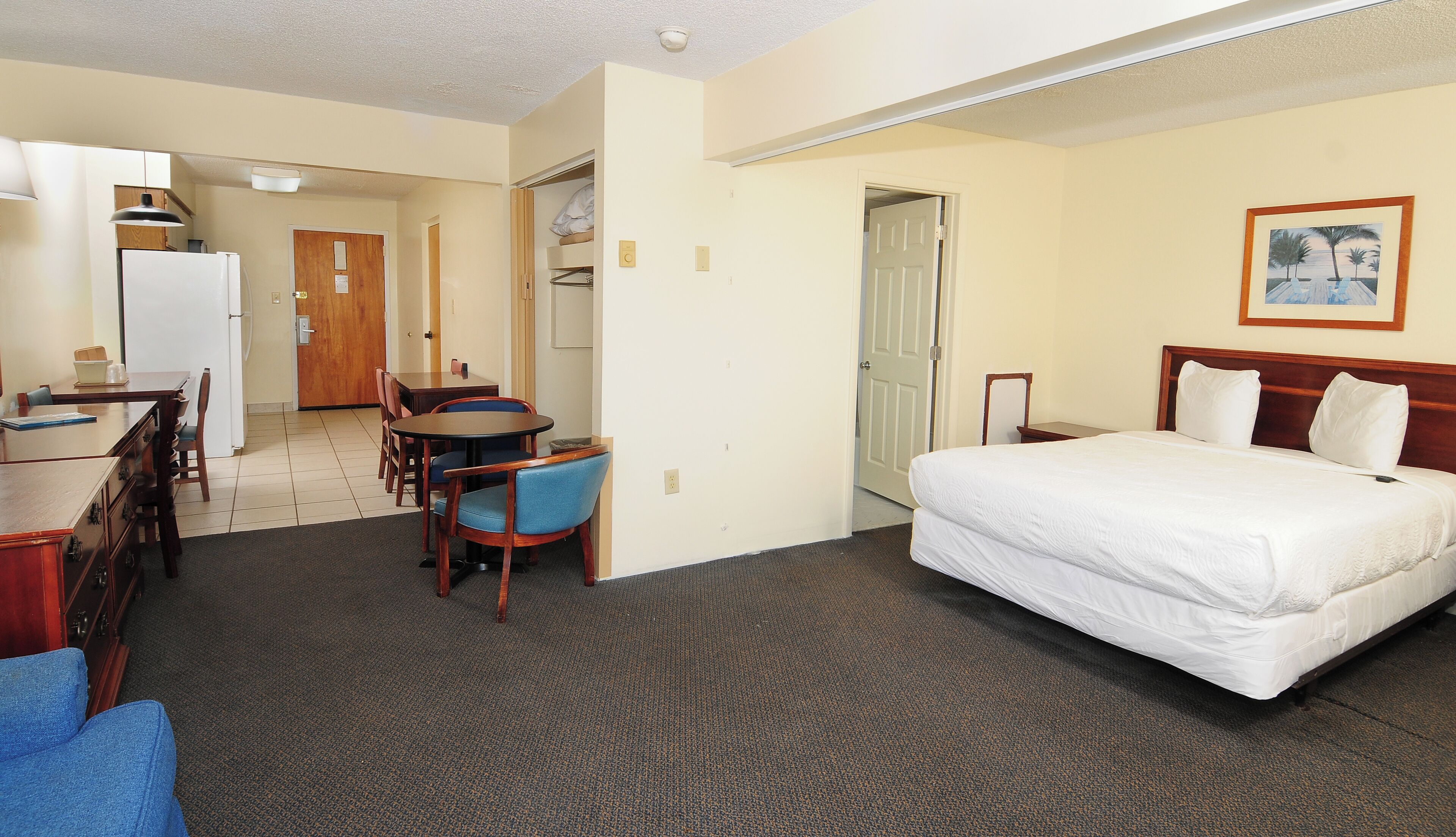 Een hotelkamer met een bed, een bureau, een stoel, een bijzettafeltje en een deur naar een badkamer.