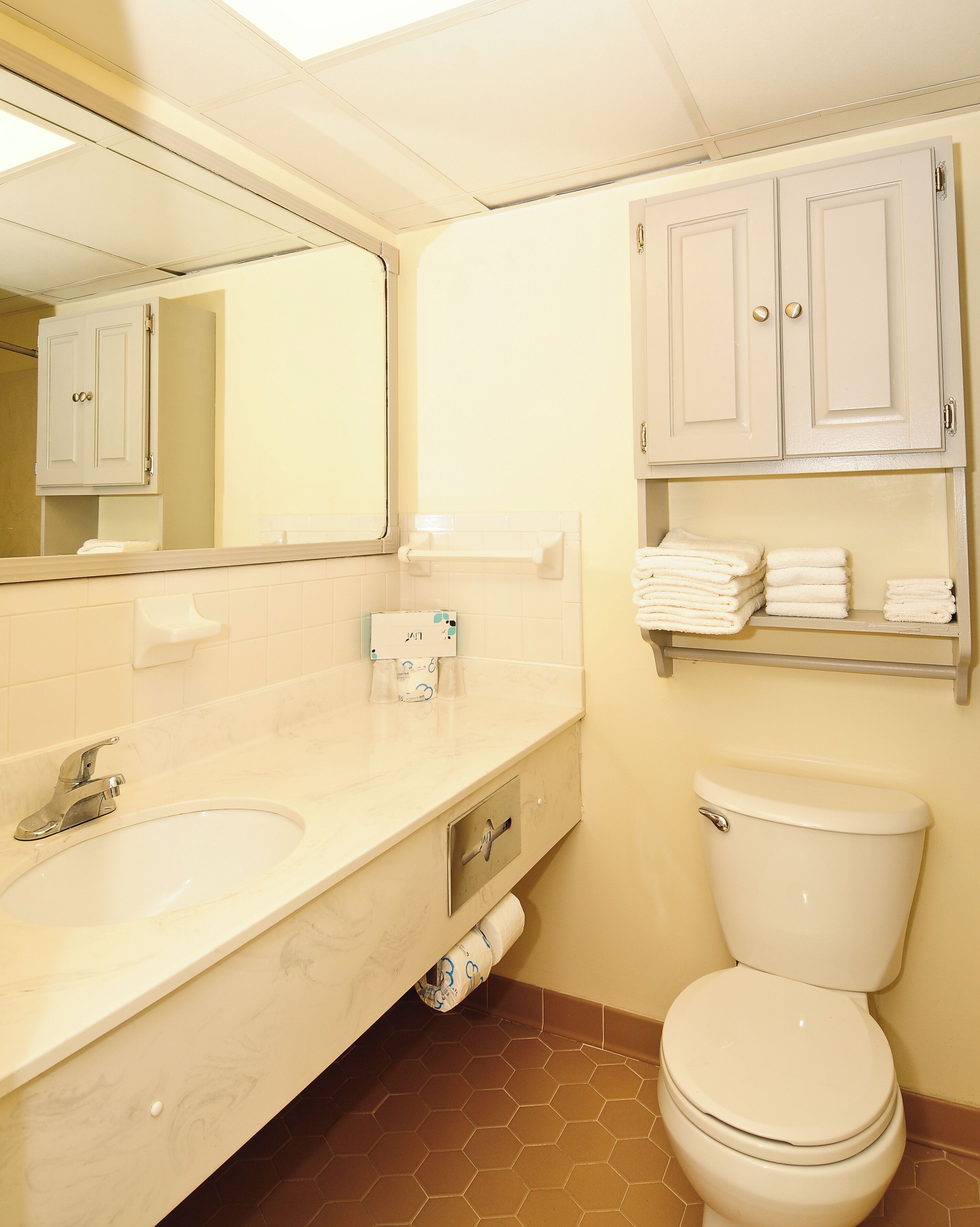 Une salle de bain équipée d’un lavabo, d’un miroir, de toilettes et de meubles de rangement.