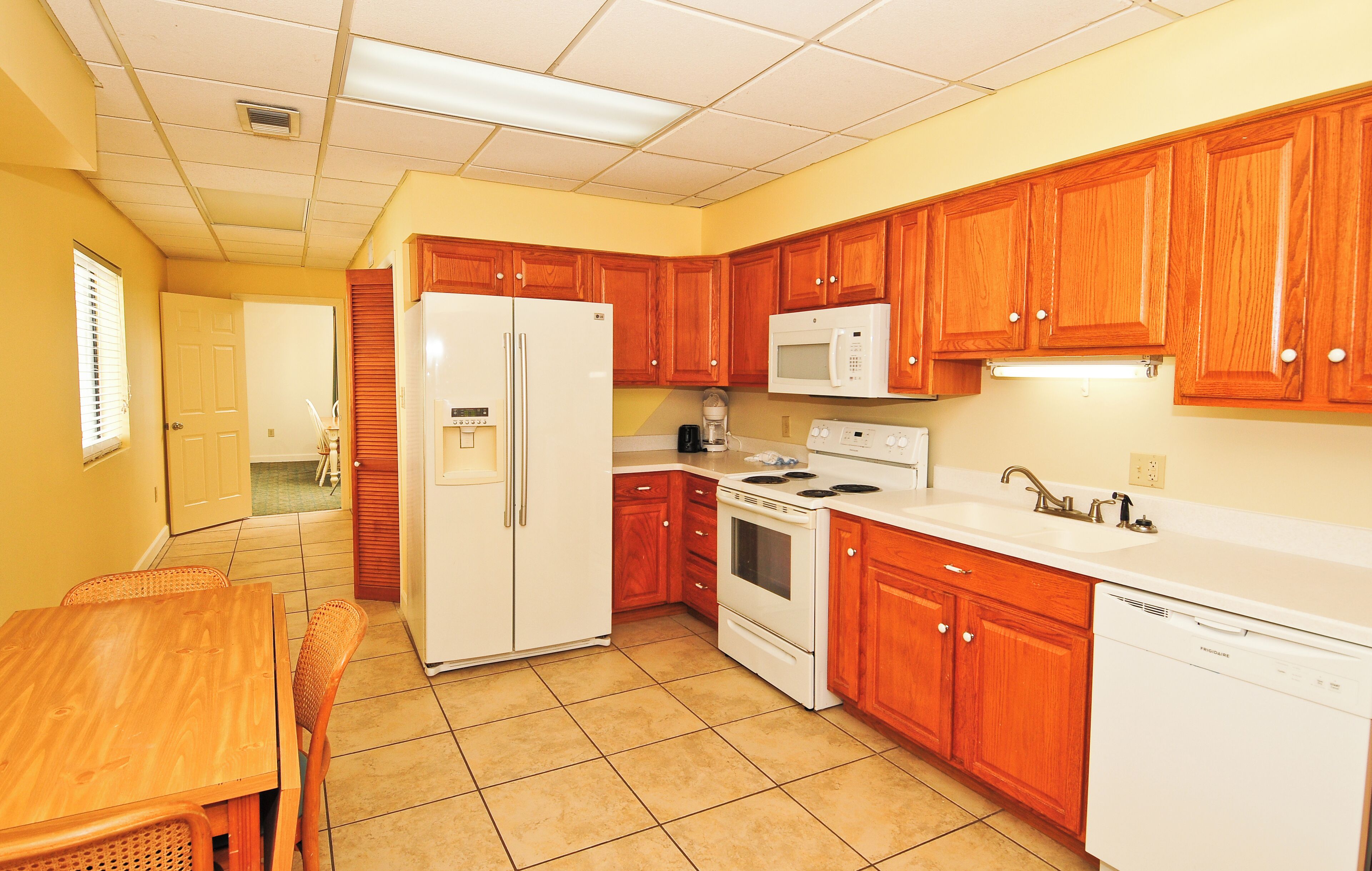 A kitchen with wooden cabinets, a white refrigerator, a microwave, a stove, and a dishwasher.