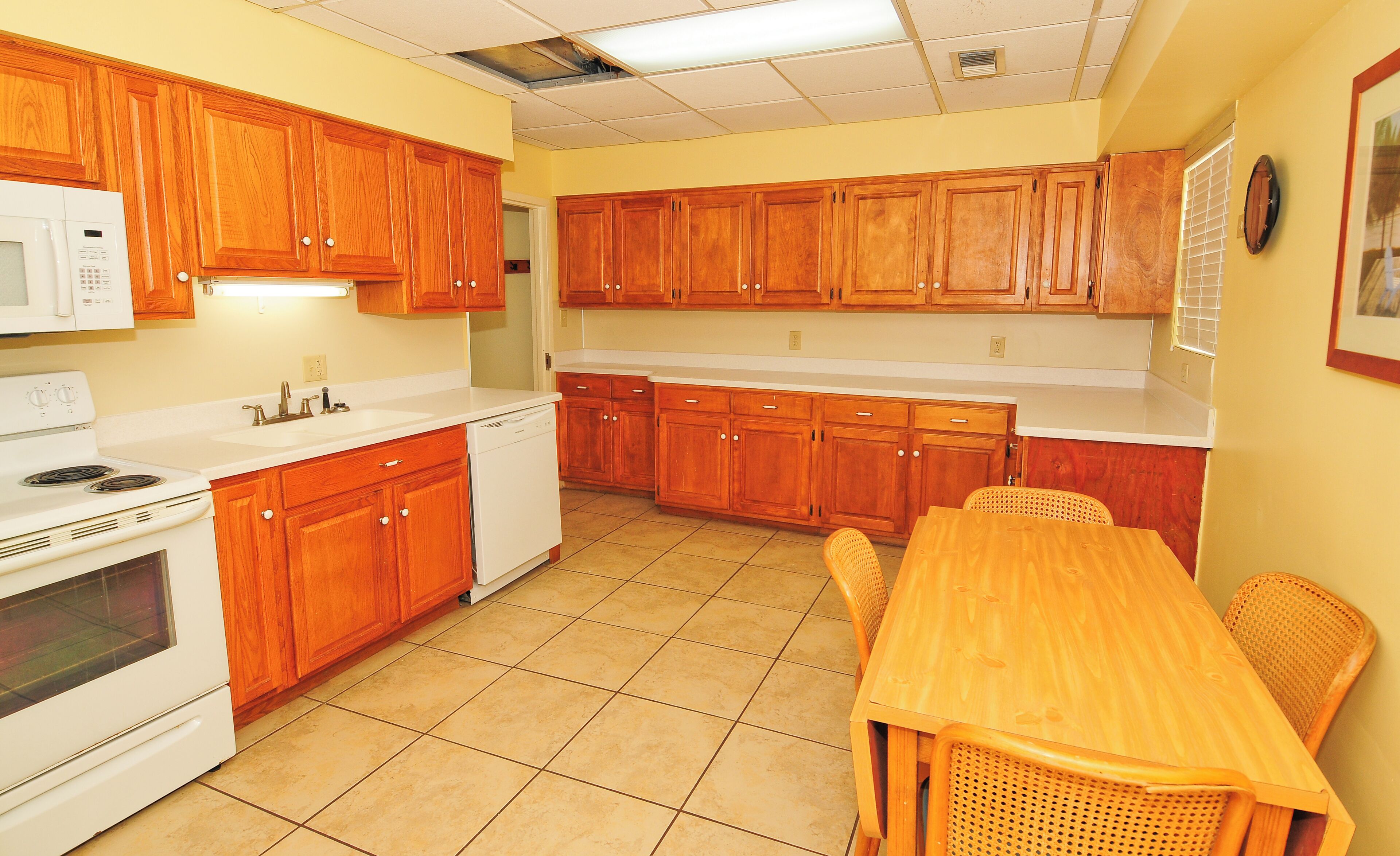 A kitchen with wooden cabinets, a white stove, a dishwasher, and a dining table with chairs.