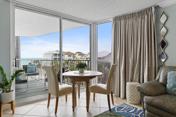A balcony with a table and chairs, a sofa, and a view of the sea and buildings. - Mainsail 433 - Gulf-Front, Wonderful Onsite Amenities, Free Beach Service! (Miramar Beach)