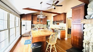 A spacious kitchen with wooden cabinets, a large island, and a ceiling fan. - Lake Winnisquam water front home  (Belmont)