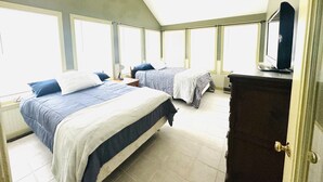 A bedroom with two beds, a dresser, a mirror, and a ceiling fan. - Lake Winnisquam water front home  (Belmont)