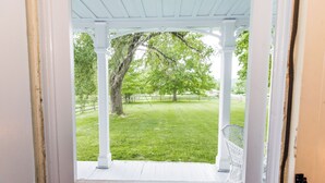 A porch with white columns and a view of a green lawn and trees. - Historic Parker’s Landing
(Springfield)
