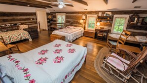 A cozy bedroom with a large bed, a wooden ceiling, a desk, and a chair. - Historic Parker’s Landing
(Springfield)