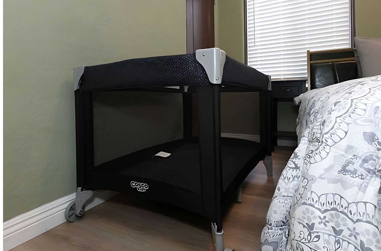 A bunk bed with a Cosco brand mattress, a small table beside it, and a patterned bedspread.