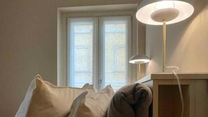 Un dormitorio con cama, dos almohadas, una mesita de noche y una lámpara.