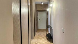 Un pasillo con suelo de espiga, iluminación empotrada y una puerta al final.