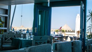 A restaurant with a view of pyramids, featuring tables and chairs arranged for dining. - Pyramids Chill Out (Giza)