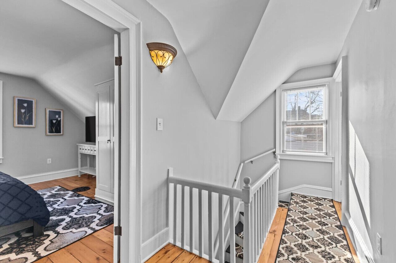 A bedroom with a bed, a dresser, a nightstand, a lamp, and a window.