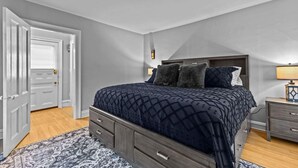 Una camera da letto con un letto, un comodino, una cassettiera e una porta.