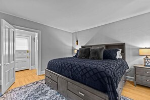 A bedroom with a bed, a nightstand, a dresser, and a door. - Charming 4BR House - Burlington (Burlington)