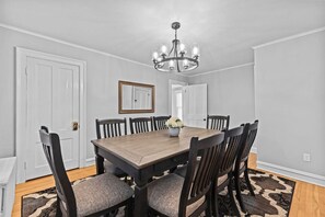 A dining room with a wooden table and chairs, a chandelier, and a mirror on the wall. - Charming 4BR House - Burlington (Burlington)