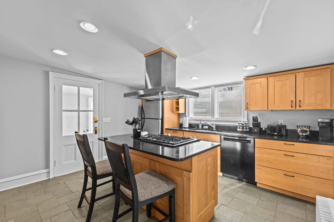 A modern kitchen with a central island, wooden cabinets, and a built-in stove.