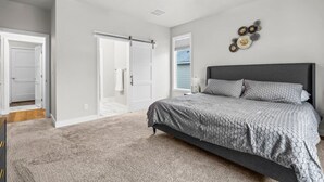 Une chambre à coucher avec un lit, un ventilateur de plafond, une porte et un élément décoratif mural.