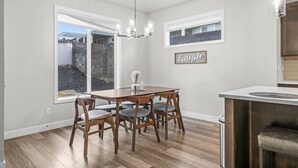 Un coin repas avec une table et des chaises en bois, un lustre et un panneau mural sur lequel est écrit le mot « Rire ».