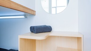 Un baño con tocador de madera, una toalla y un espejo en la pared.