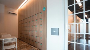 Un vestíbulo de hotel con una fila de taquillas, una pequeña zona de estar y una puerta de vidrio que da a otra habitación.