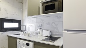 Une cuisine moderne équipée d’un lave-linge et d’un sèche-linge intégrés, d’un four à micro-ondes et d’un réfrigérateur.