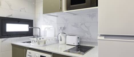 A modern kitchen with a built-in washer and dryer, a microwave, and a refrigerator.
