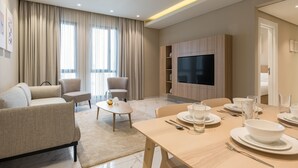 Un salon moderne comprenant un canapé, des fauteuils, une table basse et un coin repas aménagé pour quatre personnes.