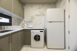 A compact kitchen with a washing machine, a refrigerator, and a microwave.