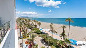 Vista de una playa con palmeras, una piscina y cielo despejado.